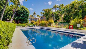 A rectangular swimming pool with a clear blue water surface, surrounded by lush greenery and palm trees. - Direct Oceanfront Maui Studio,Romantic,Breathtaking View from Huge Private Lanai (Lahaina)