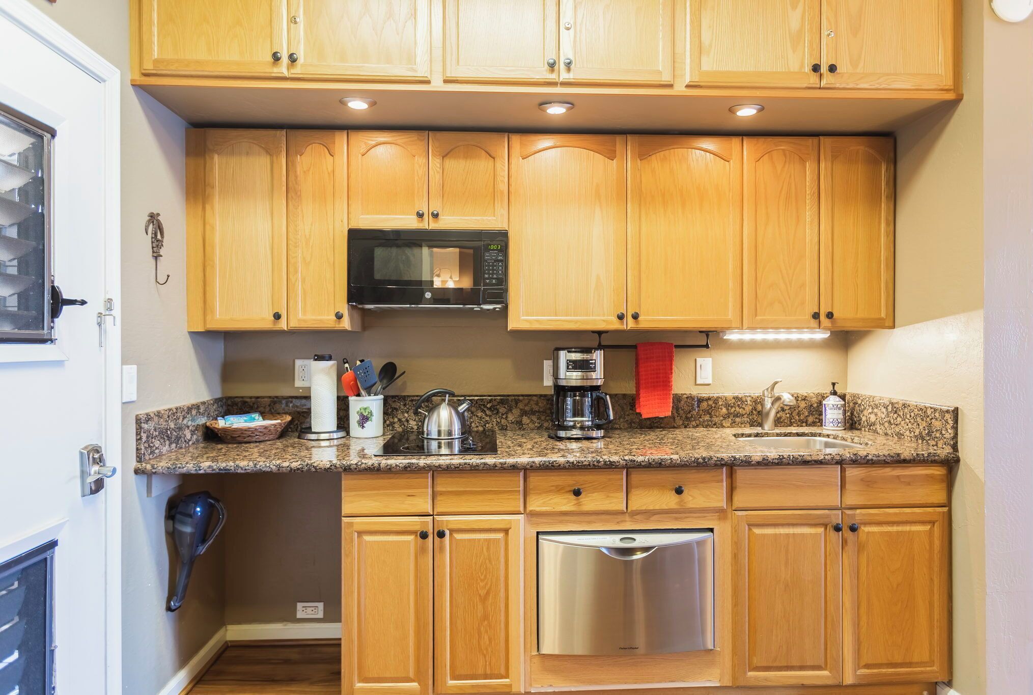 A kitchen with wooden cabinets, a microwave, a coffee maker, and a dishwasher.