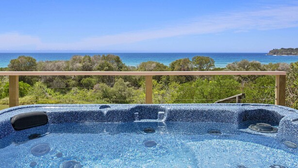A hot tub with a clear view of the ocean and greenery. - 3 bedroom beachfront property - Stunning Ocean views - direct access to beach (Kiama Downs)