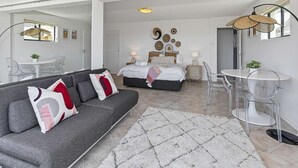 A modern bedroom with a bed, bedside tables, and a sofa. - 3 bedroom beachfront property - Stunning Ocean views - direct access to beach (Kiama Downs)