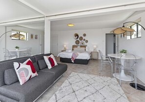 A modern bedroom with a bed, bedside tables, and a sofa.