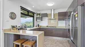 A modern kitchen with a large island, stainless steel appliances, and a view of greenery outside. - 3 bedroom beachfront property - Stunning Ocean views - direct access to beach (Kiama Downs)