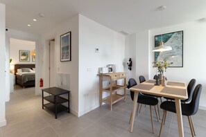 A modern dining area with a wooden table and black chairs, a small shelf unit, and a pendant light. - Marinsa Beach, 1 bedroom apartment close to the ocean (Torrox)