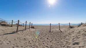 A sandy beach with wooden posts and ropes, leading to the ocean.