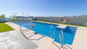 A rectangular swimming pool with a clear blue water, surrounded by a tiled deck.