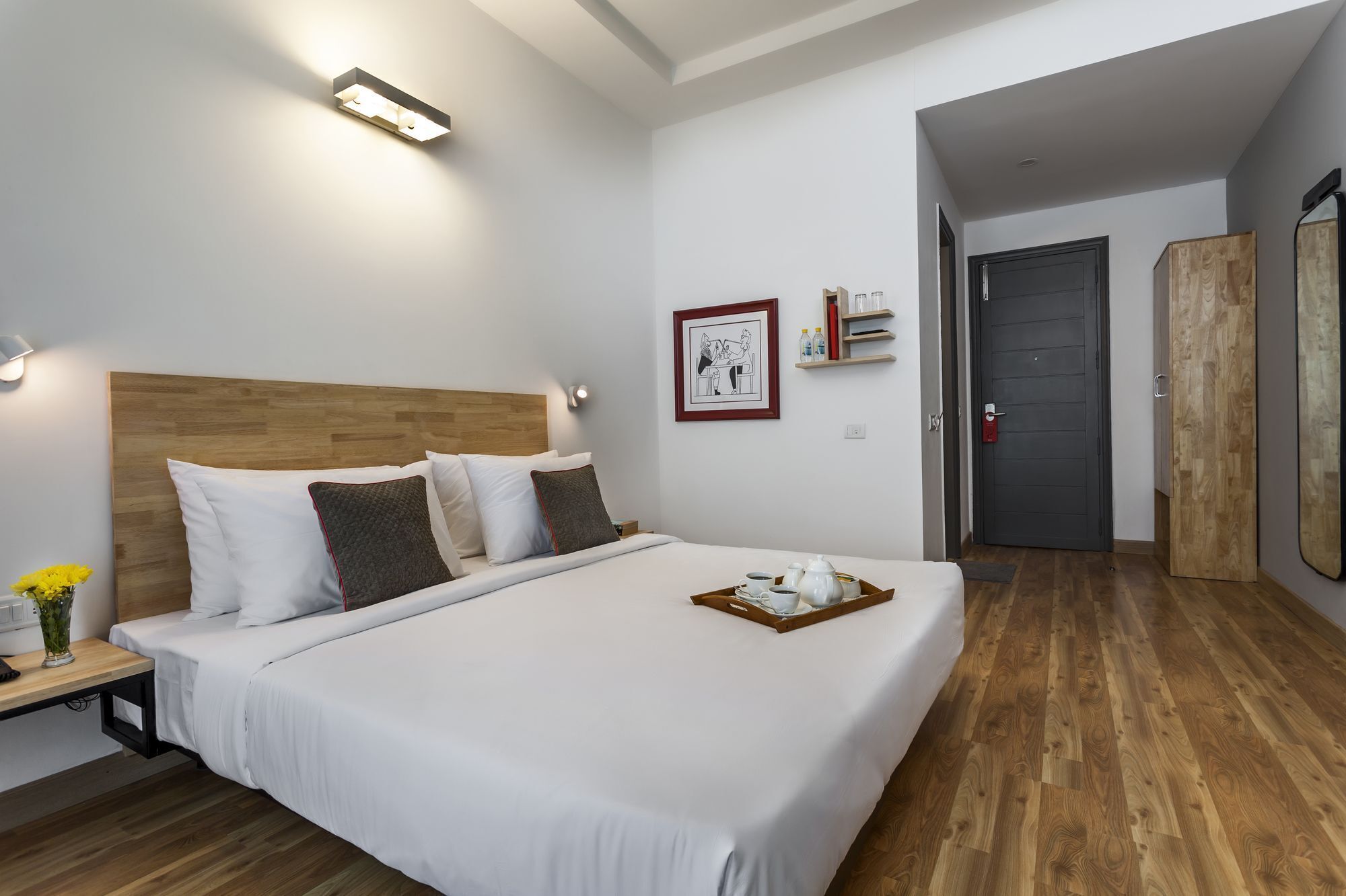 A neatly arranged hotel room with a large bed, bedside table, and a small desk with a lamp.