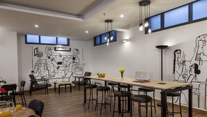 Una sala de reuniones moderna con una larga mesa, sillas negras y un mural en la pared.