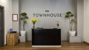 Una recepción con un letrero que dice "OYO TOWNHOUSE" y dos plantas en macetas a cada lado.