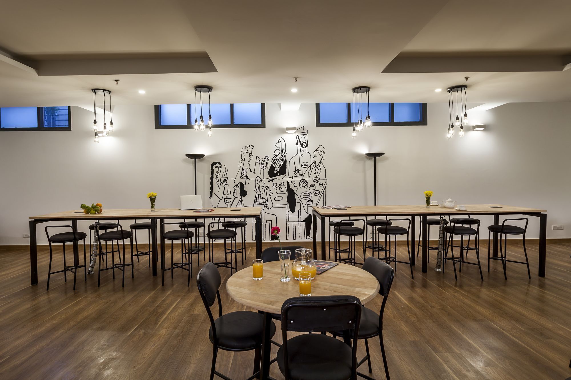 A conference room with a long table, multiple chairs, and a round table with drinks.