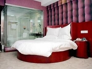 A modern bedroom with a circular bed, a glass shower enclosure, and a red accent wall. - Greentree Inn Nantong Middle Renmin Road Branch (Nantong)