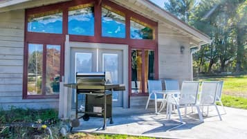 Una casa con patio, dotata di barbecue, area relax all'aperto e ampie finestre.
