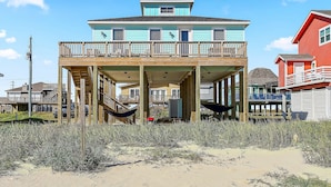 A beachfront house with a balcony, a hammock, and a view of the beach.