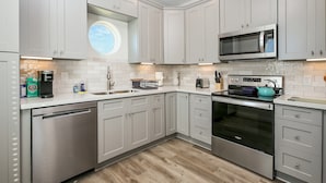 A modern kitchen with light grey cabinets, a stainless steel dishwasher, a built-in oven, and a microwave.
