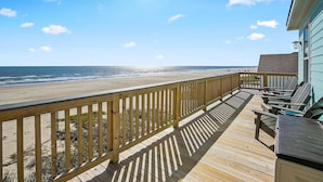 A wooden deck with a view of the beach and ocean.