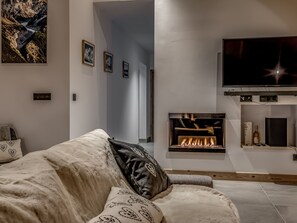 A modern living room with a fireplace, a flat-screen TV mounted on the wall, and a cozy sofa with patterned cushions.