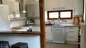 A compact kitchen with white cabinets, a built-in microwave, a dishwasher, and a window above the sink.