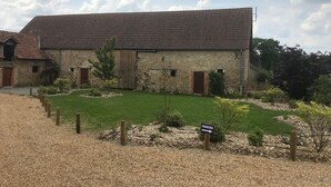 A stone building with a tiled roof, a grassy yard, and a sign indicating parking.