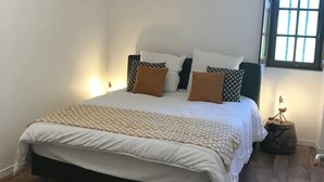 A neatly made bed with a patterned bedspread, two pillows, and a bedside lamp.