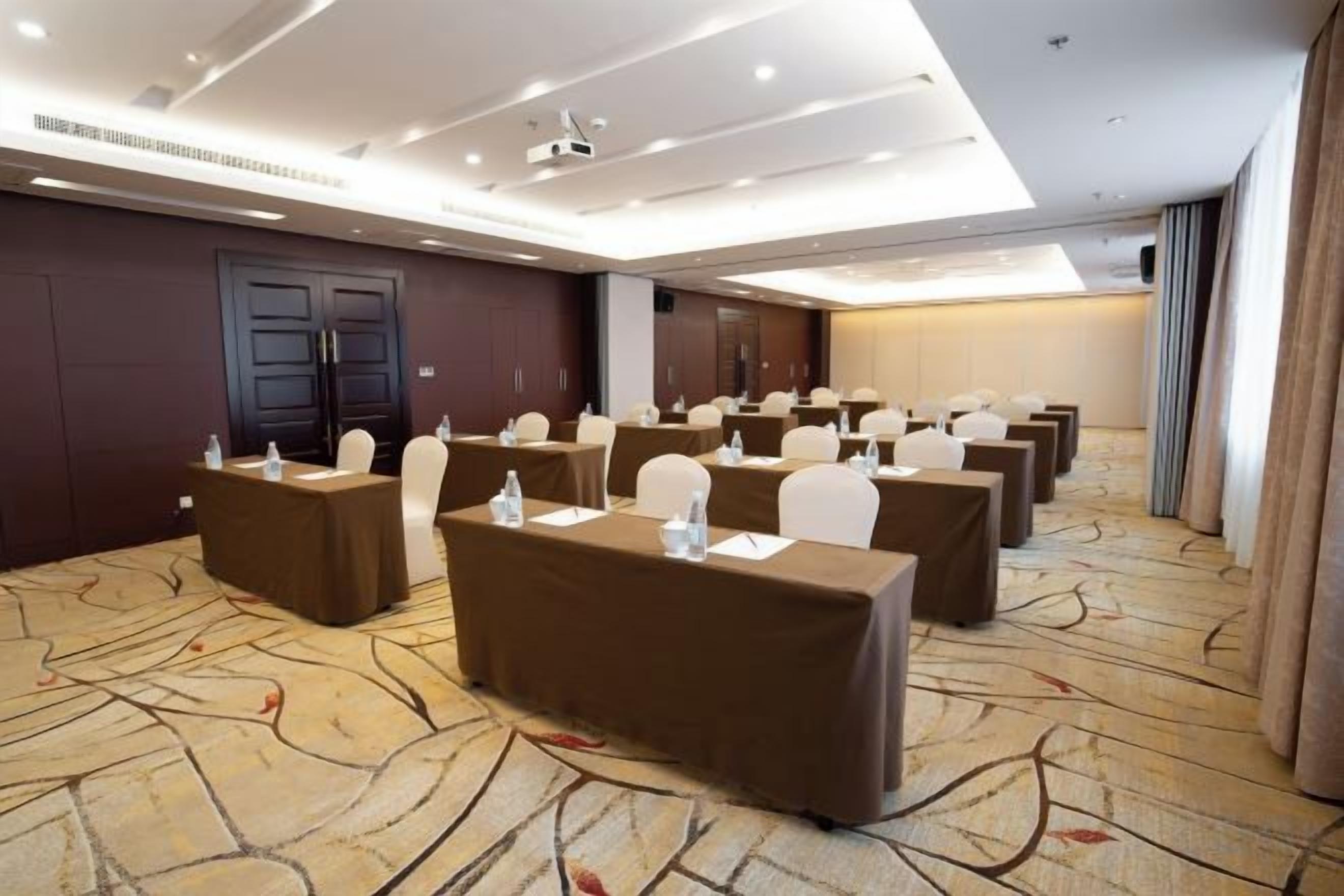 A conference room with multiple tables, chairs, and a carpeted floor.