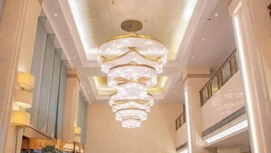 Um interior espaçoso com um grande e ornamentado candelabro pendurado no teto, pé-direito alto e design moderno com linhas retas.