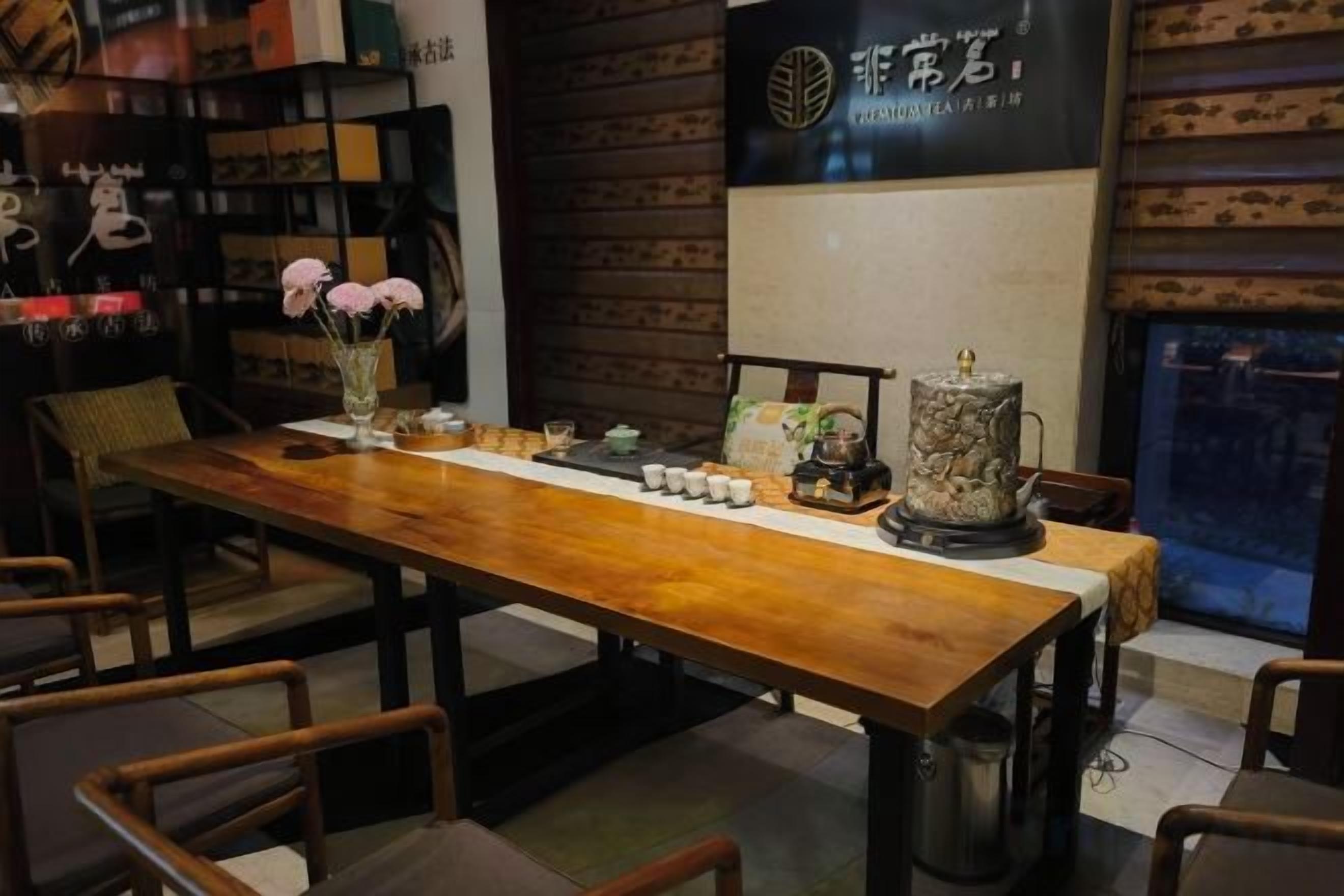 Una mesa de madera con sillas, un jarrón con flores y una tetera.