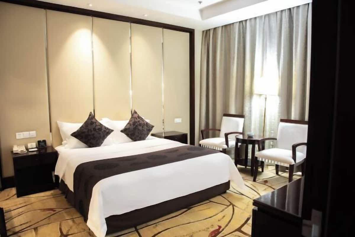 A hotel room with a large bed, two nightstands, a desk, and a chair.