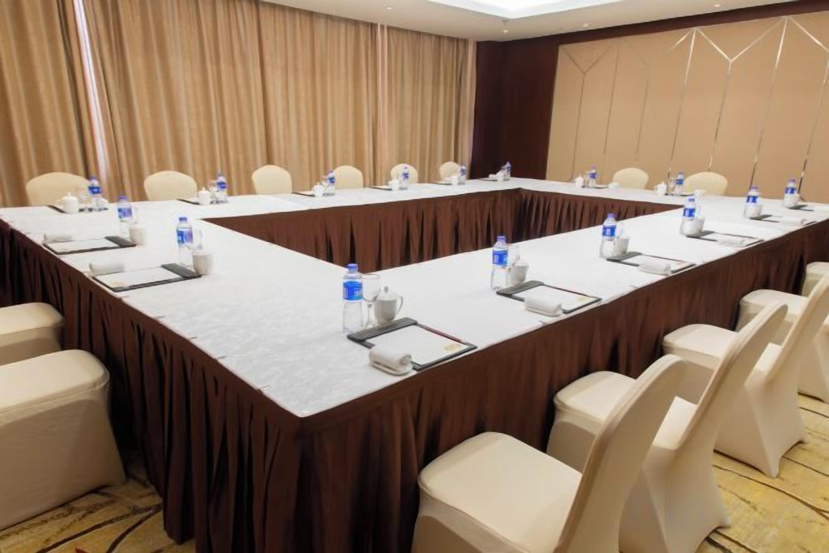 A conference room with a long table, chairs, water bottles, and nameplates.