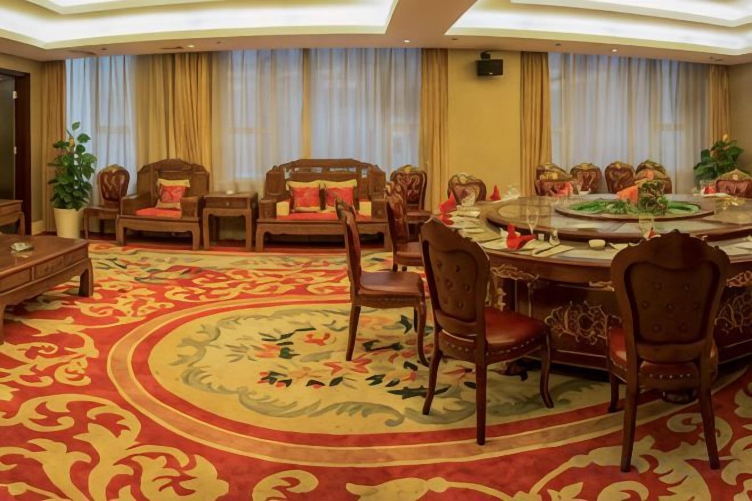 A hotel dining area with a round table, chairs, and a carpeted floor.