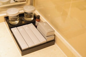 Une salle de bain avec un lavabo, deux flacons de savon liquide et plusieurs boîtes de produits de toilette.