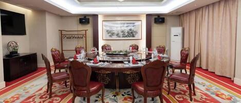 A conference room with a round table, red chairs, a chandelier, and a carpeted floor.