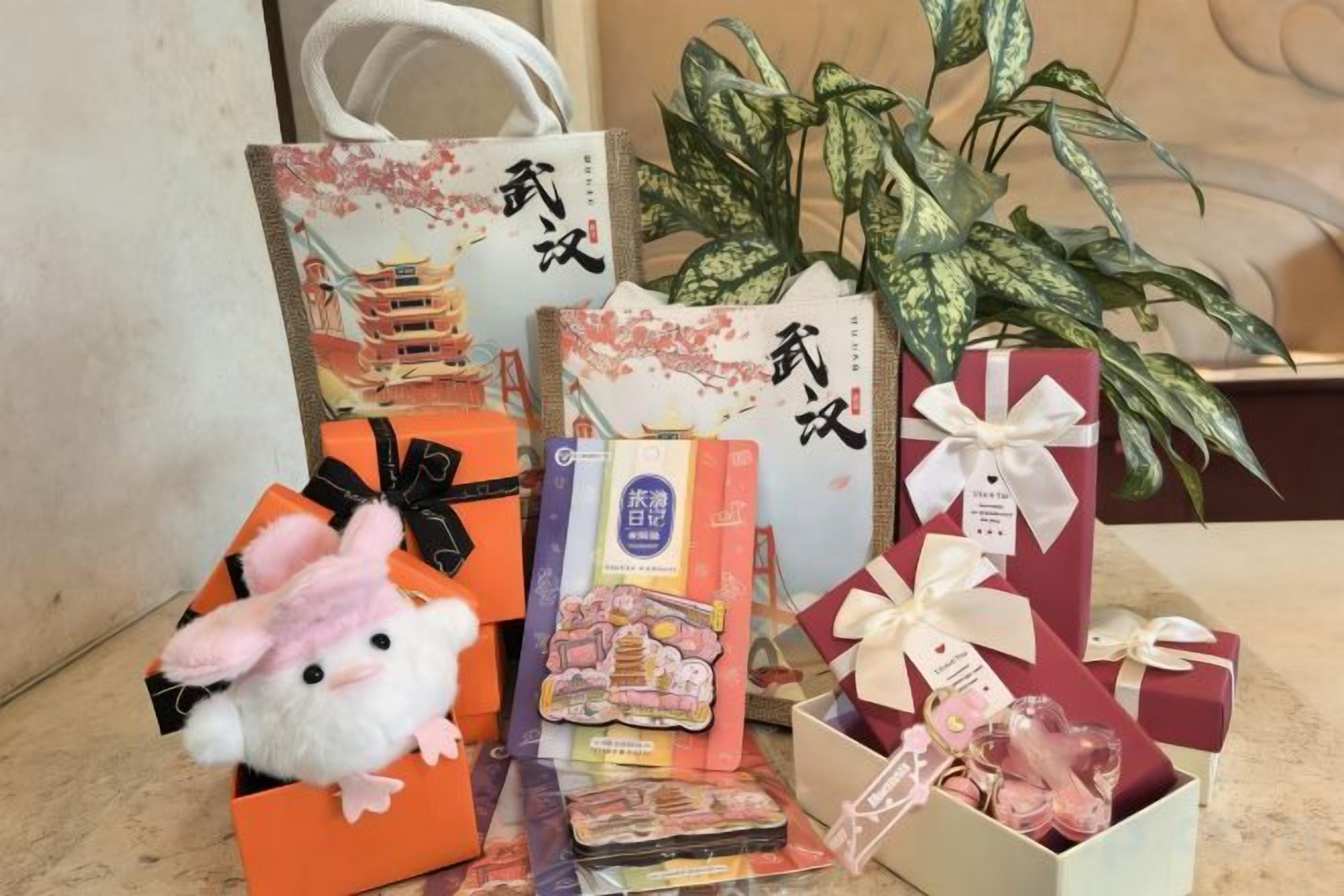 A variety of gift bags and boxes, some with ribbons, placed on a surface with a potted plant in the background.