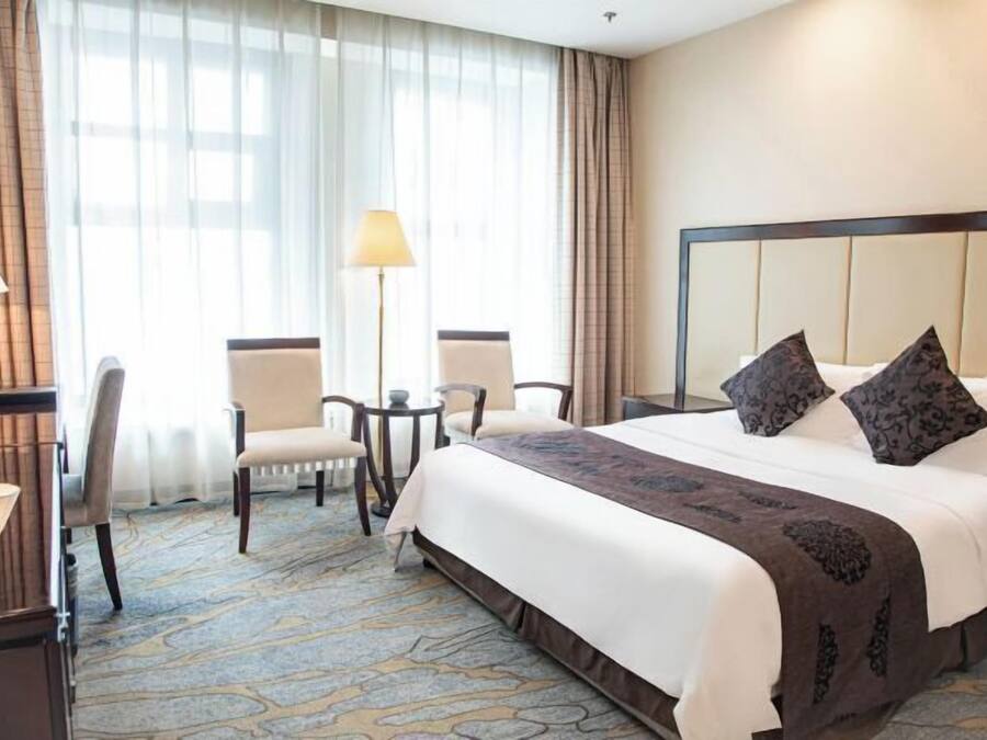 Een hotelkamer met een groot bed, twee stoelen, een bureau en een lamp.