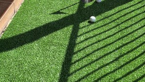 Un parcours de minigolf avec un gazon synthétique vert, un mât de drapeau et des balles de golf.