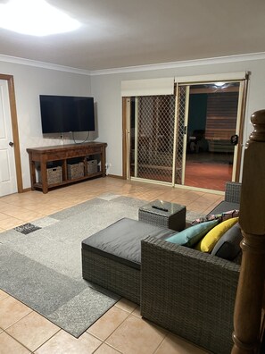 Relax in the living room with a flat-screen TV, a comfortable sectional sofa, and a sliding door leading to an outdoor area.