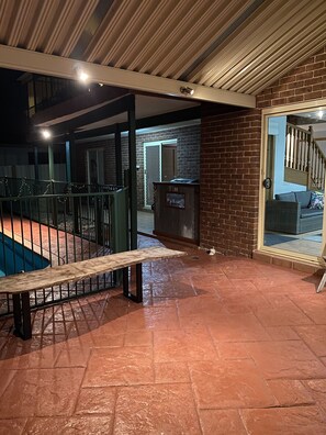 Relax by the pool in a serene outdoor space with a bench and staircase leading to an upper level.