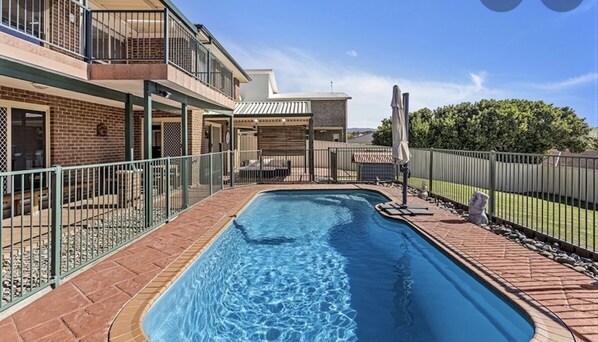 Enjoy a refreshing swim in the pool surrounded by a paved deck and a covered seating area.
