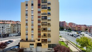 Un edificio residencial de varios pisos con balcones, una zona de estacionamiento y vista a la calle.
