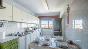 Una cocina con armarios blancos, encimera de mármol y una mesa de comedor para cuatro.