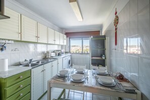A kitchen with white cabinets, a marble countertop, and a dining table set for four.
