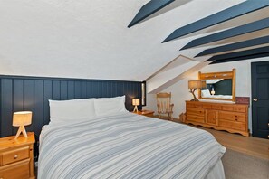 A bedroom with a bed, nightstand, dresser, and a mirror.