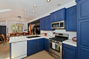 Una cocina moderna con armarios azules, lavavajillas, estufa y microondas.