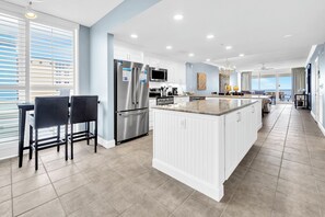 Une cuisine moderne avec des meubles blancs, des appareils en acier inoxydable et un grand îlot central.
