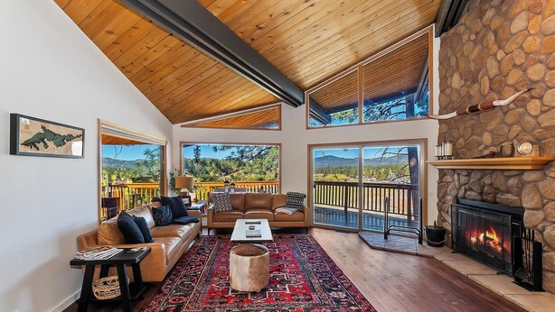 A spacious living room with a stone fireplace, leather sofas, a coffee table, and a large rug.