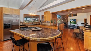 A spacious kitchen with a large island, stainless steel appliances, and a stone fireplace.
