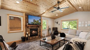 Un salon chaleureux avec une cheminée, un plafond en bois et de grandes fenêtres.