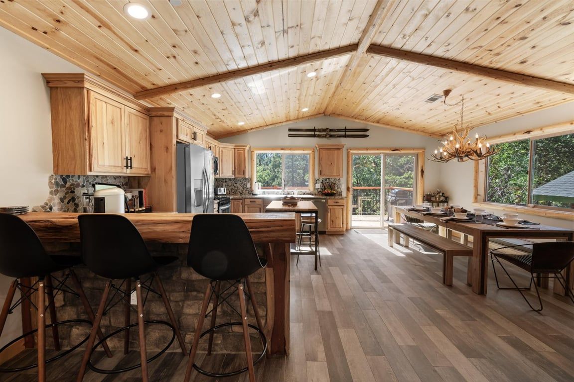 A spacious kitchen with wooden cabinets, a large island with bar stools, and a dining area with a long table and benches.
