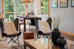 Een moderne woonkamer met twee leren fauteuils, een houten salontafel en een eethoek op de achtergrond.