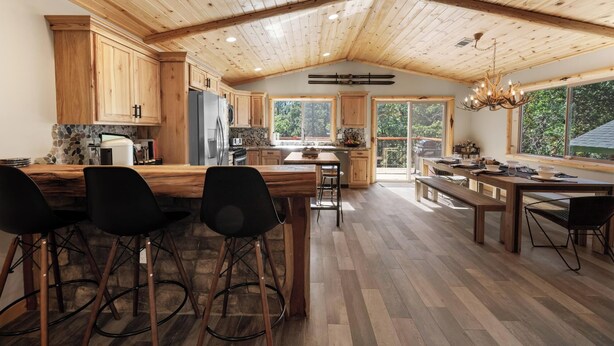 Une cuisine spacieuse avec des meubles en bois, un grand îlot central et un coin repas équipé d’une banquette.