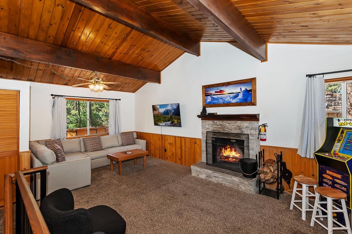 A cozy living room with a fireplace, a sofa, a coffee table, and a game console.