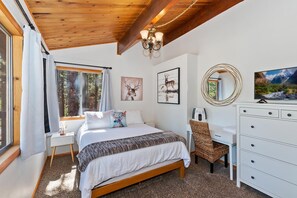 A bedroom with a bed, a dresser, a chair, and artwork on the walls.